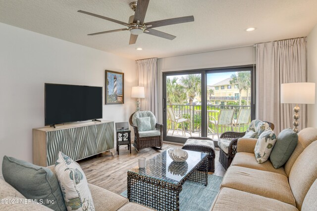 living room with ceiling fan, light hardwood / wood-style floors, a textured ceiling, and a healthy amount of sunlight