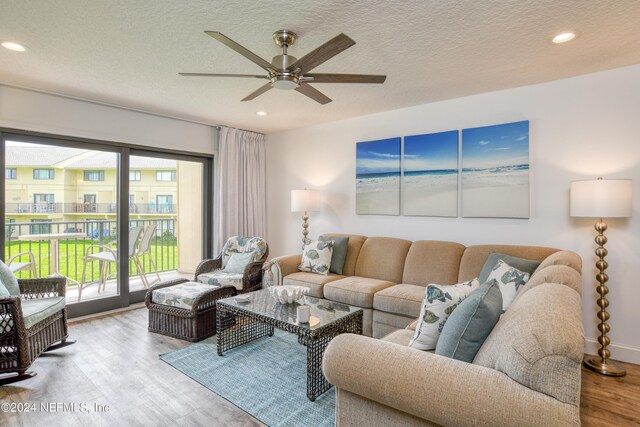 living room with a textured ceiling, hardwood / wood-style flooring, and ceiling fan