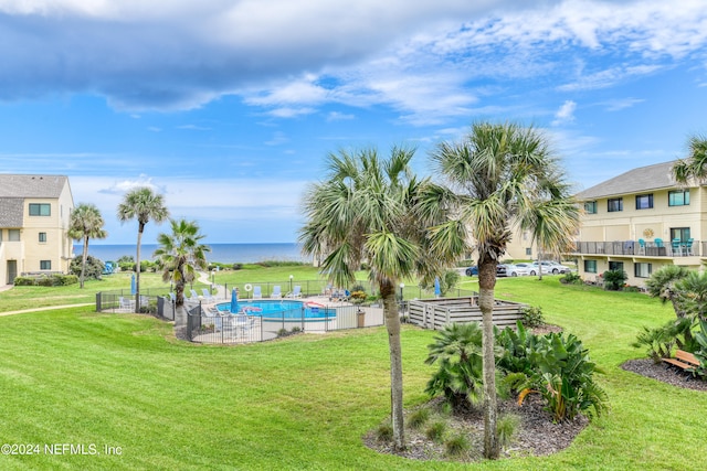 view of home's community with a water view, a lawn, and a pool