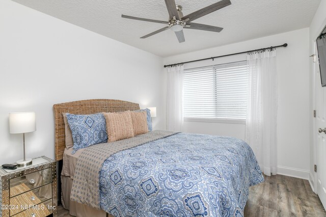 bedroom with a textured ceiling, ceiling fan, and wood-type flooring