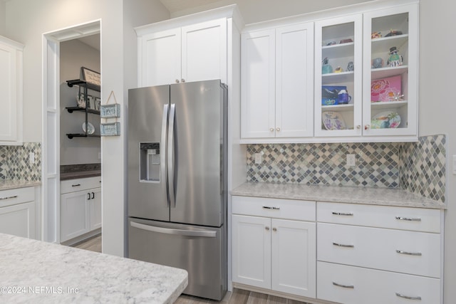 kitchen featuring white cabinetry, tasteful backsplash, light hardwood / wood-style flooring, and stainless steel fridge