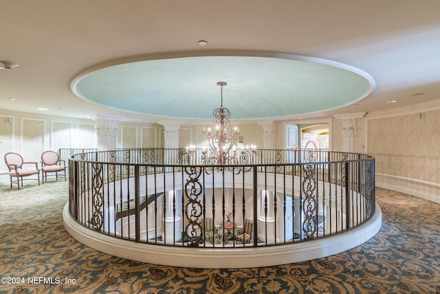 hallway featuring a notable chandelier, crown molding, an upstairs landing, and ornate columns