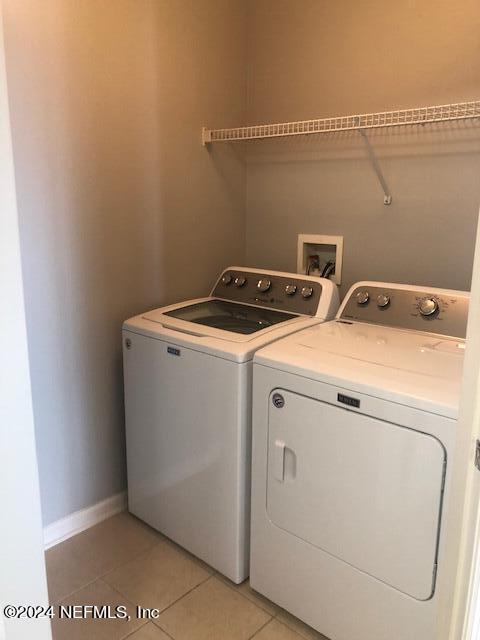 laundry area featuring light tile patterned floors, baseboards, washer and dryer, and laundry area