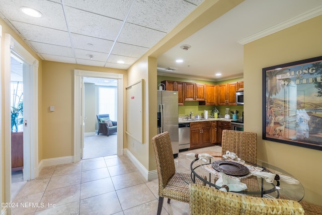 kitchen with light countertops, light tile patterned floors, stainless steel appliances, a sink, and brown cabinetry