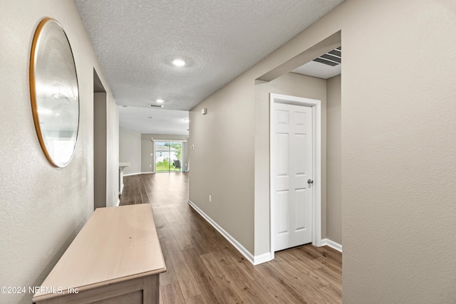 hall featuring a textured ceiling and hardwood / wood-style floors