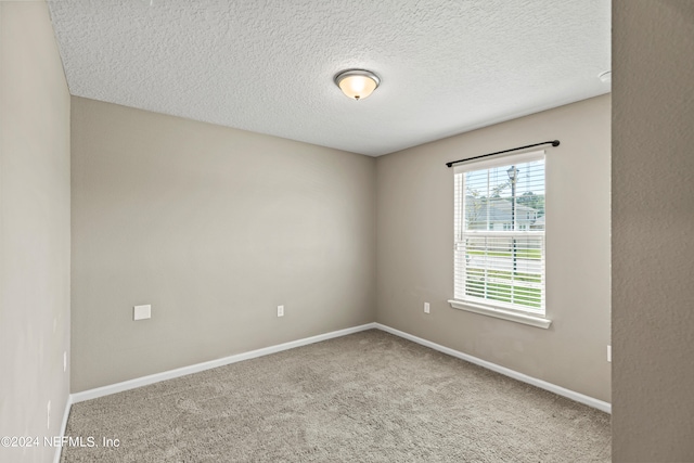 carpeted empty room featuring a textured ceiling