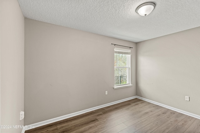 empty room featuring a textured ceiling and light hardwood / wood-style flooring