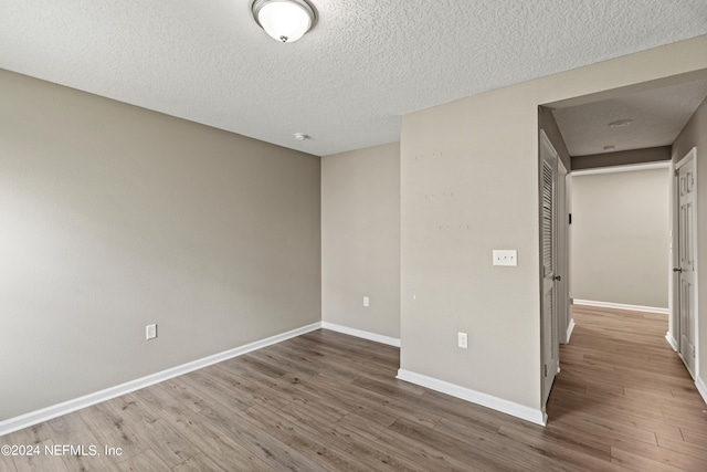 empty room with wood-type flooring and a textured ceiling