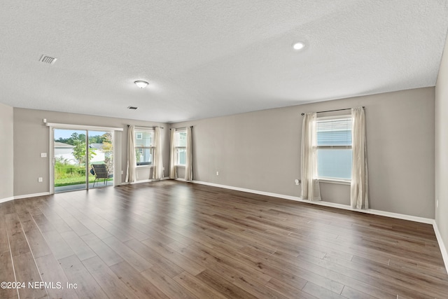 spare room featuring a textured ceiling and dark wood-type flooring