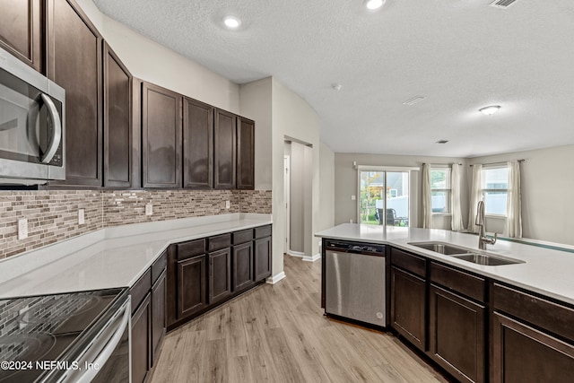 kitchen featuring dark brown cabinets, sink, light hardwood / wood-style flooring, stainless steel appliances, and decorative backsplash