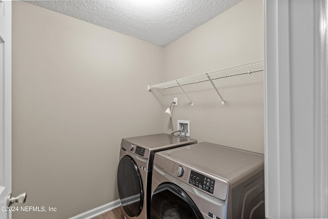 laundry room featuring a textured ceiling, wood-type flooring, and separate washer and dryer