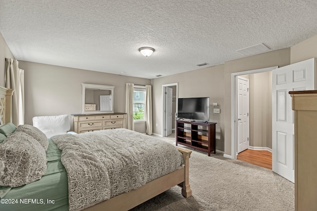 bedroom with a textured ceiling and light carpet