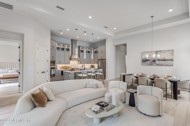 living room featuring light hardwood / wood-style flooring, sink, and a chandelier