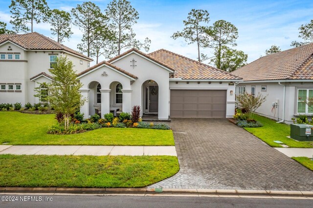 mediterranean / spanish house with a garage and a front yard