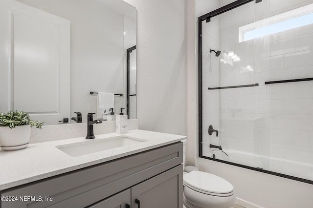 full bathroom featuring vanity, toilet, and combined bath / shower with glass door