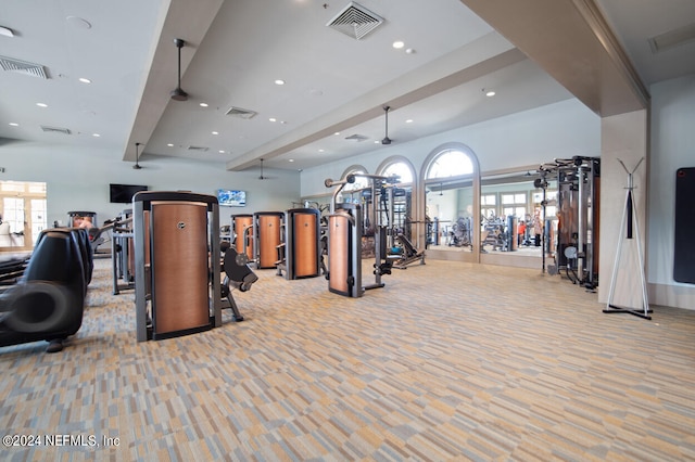 exercise room with ceiling fan and light colored carpet