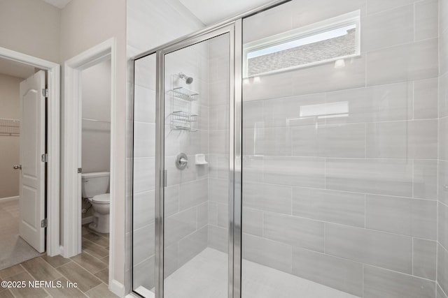 bathroom with toilet and a shower with shower door