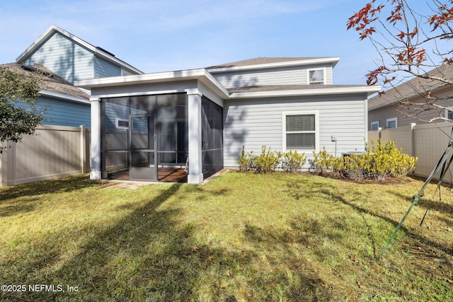 back of property with a lawn and a sunroom