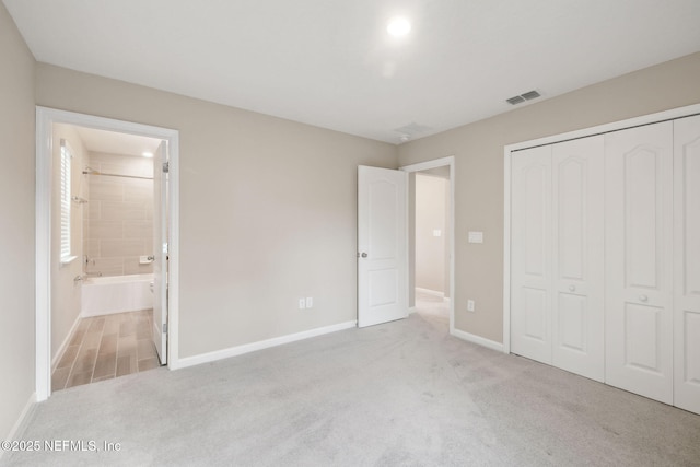 unfurnished bedroom with light colored carpet, connected bathroom, and a closet