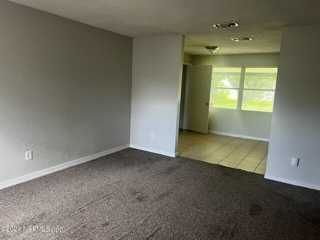 spare room featuring a textured ceiling and light carpet