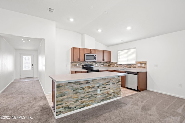 kitchen featuring light colored carpet, stainless steel appliances, lofted ceiling, a kitchen island, and decorative backsplash