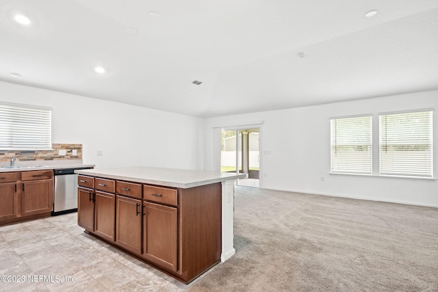 kitchen featuring a kitchen island, light carpet, stainless steel dishwasher, sink, and decorative backsplash