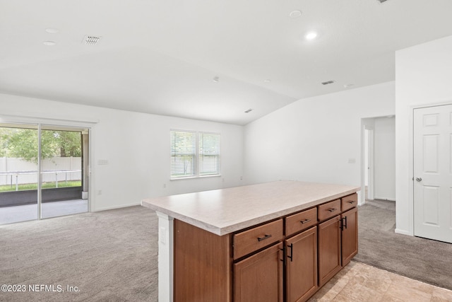 kitchen featuring lofted ceiling, a healthy amount of sunlight, a center island, and light colored carpet