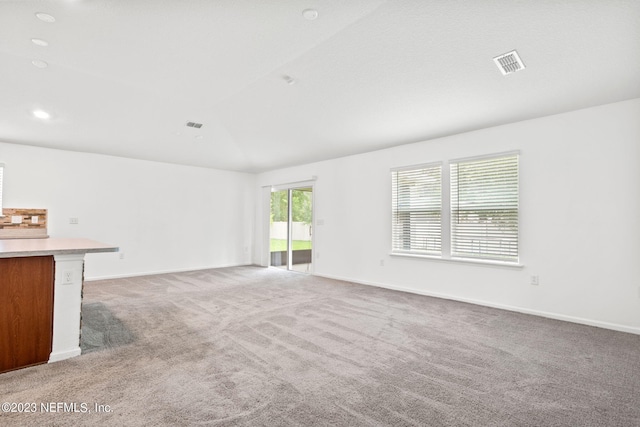 unfurnished living room featuring carpet flooring and vaulted ceiling