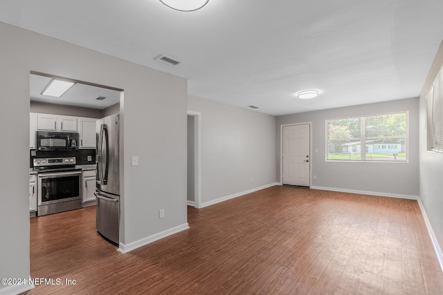 kitchen featuring dark wood-type flooring, appliances with stainless steel finishes, white cabinetry, and decorative backsplash