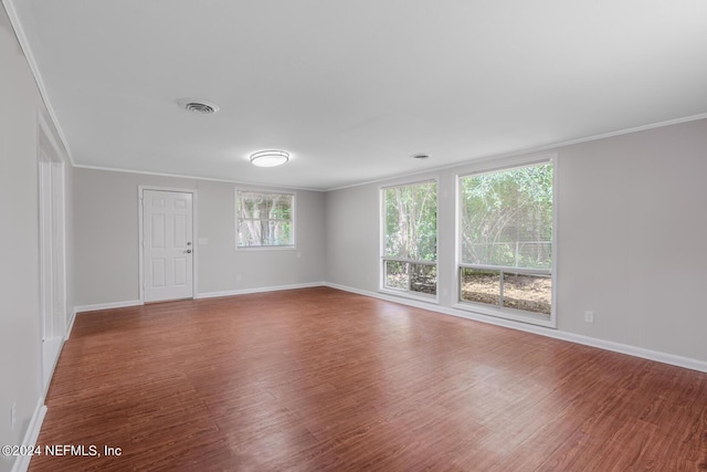 unfurnished room with visible vents, crown molding, baseboards, and wood finished floors