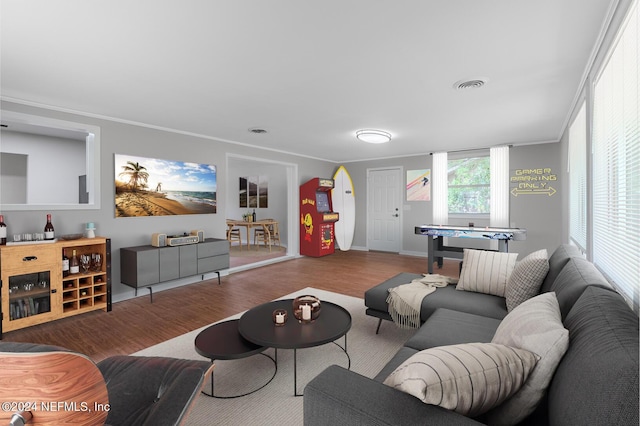 living area with visible vents, wood finished floors, and crown molding