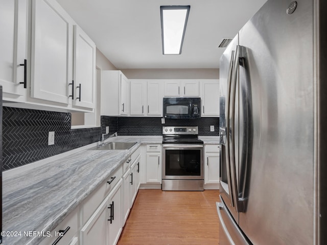 kitchen with white cabinets, stainless steel appliances, sink, and light hardwood / wood-style floors