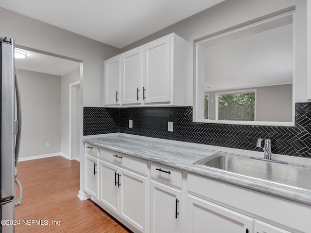 kitchen featuring sink, stainless steel fridge, light wood-type flooring, and white cabinetry