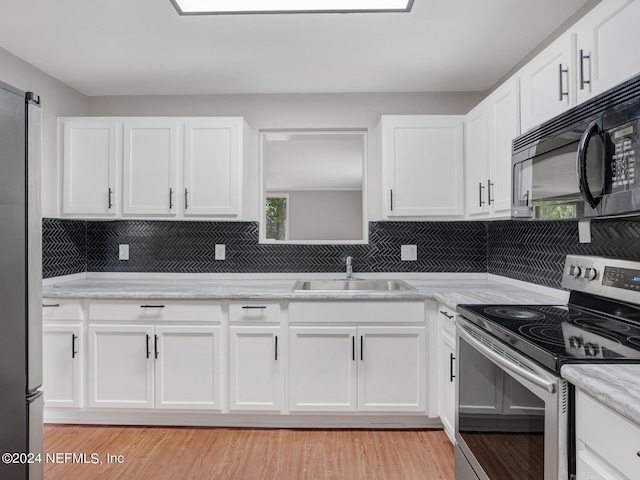 kitchen with a sink, decorative backsplash, white cabinets, and stainless steel appliances