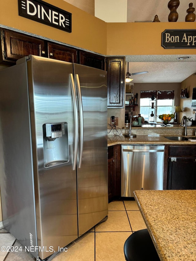 kitchen with dark brown cabinets, light tile patterned floors, sink, ceiling fan, and appliances with stainless steel finishes