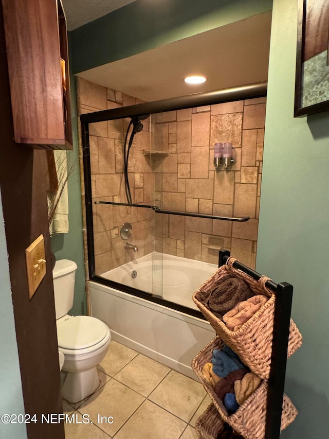 bathroom featuring toilet, bath / shower combo with glass door, and tile patterned floors