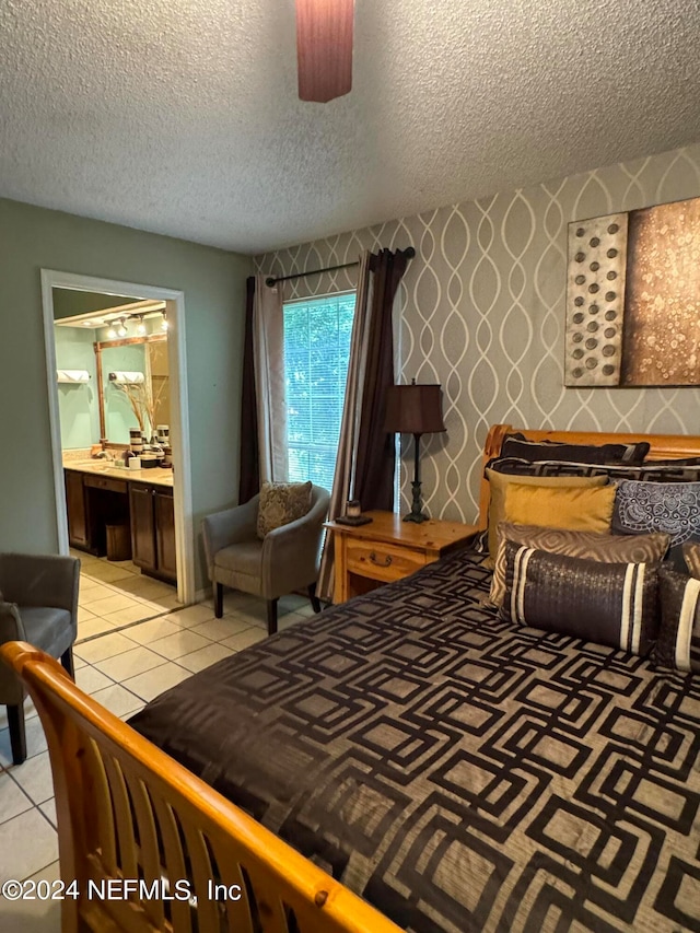 tiled bedroom featuring ensuite bathroom and a textured ceiling