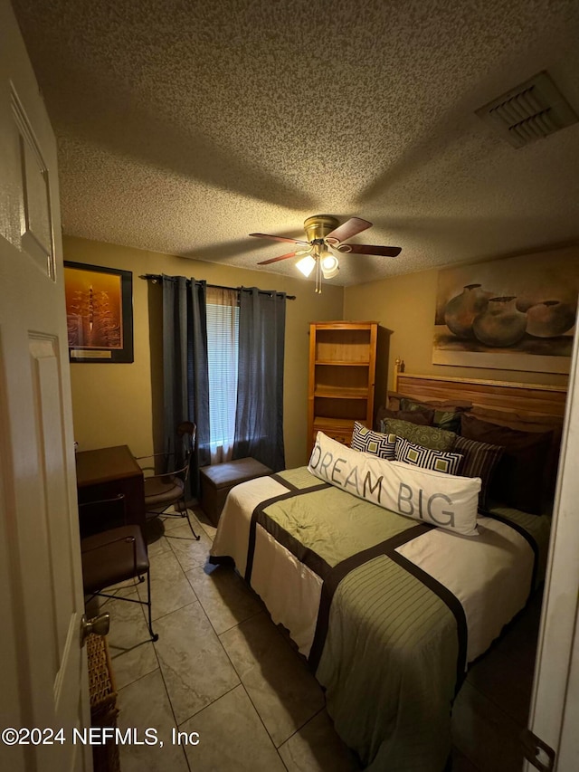 tiled bedroom with a textured ceiling and ceiling fan