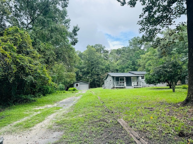 view of yard featuring a garage, a porch, and an outdoor structure