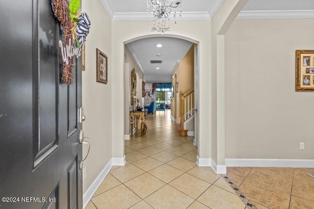 foyer with an inviting chandelier, light tile patterned flooring, and ornamental molding