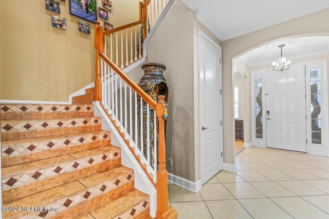 entrance foyer with light tile patterned floors, ornamental molding, and a chandelier