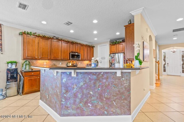 kitchen featuring ornamental molding, stainless steel appliances, kitchen peninsula, and a breakfast bar