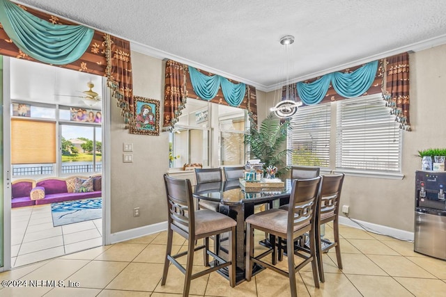 dining room with a textured ceiling, tile patterned floors, ornamental molding, and a wealth of natural light