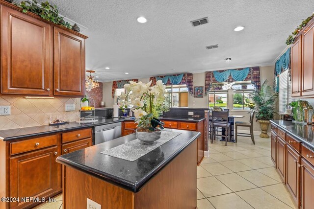 kitchen featuring kitchen peninsula, hanging light fixtures, a kitchen island, light tile patterned floors, and stainless steel dishwasher