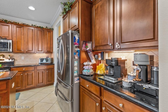 kitchen with dark stone counters, decorative backsplash, appliances with stainless steel finishes, light tile patterned floors, and ornamental molding