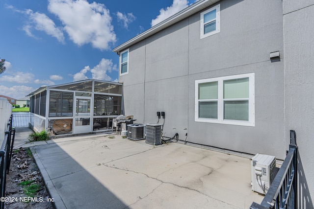 rear view of property with a sunroom, a patio, and central air condition unit