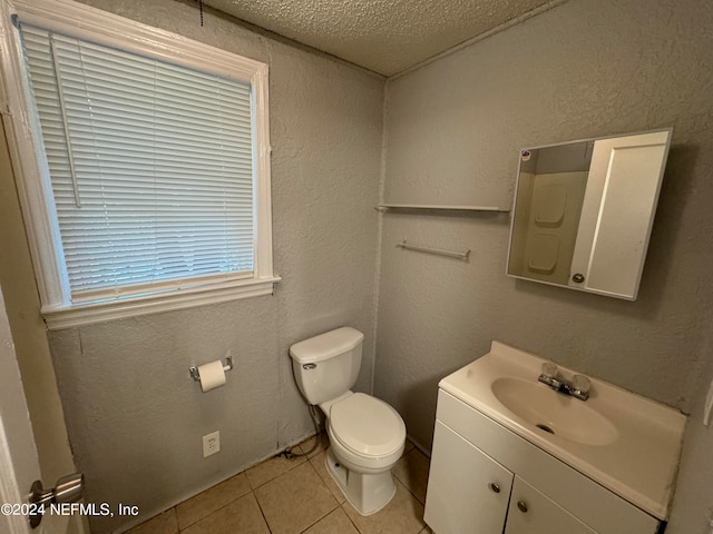 bathroom featuring tile patterned floors, toilet, a textured ceiling, and vanity