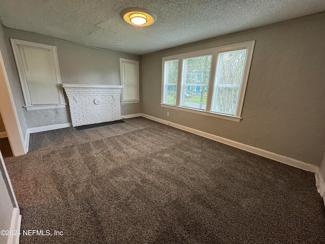 unfurnished bedroom featuring dark colored carpet, a fireplace, and a textured ceiling