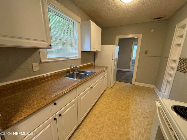 kitchen featuring white appliances, a textured ceiling, white cabinetry, and sink