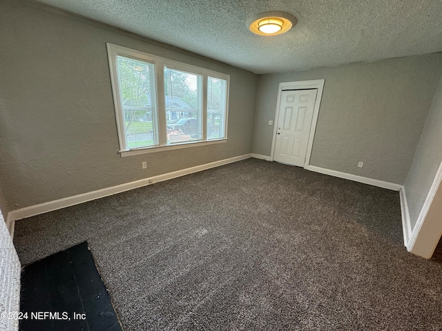 spare room featuring a textured ceiling and carpet